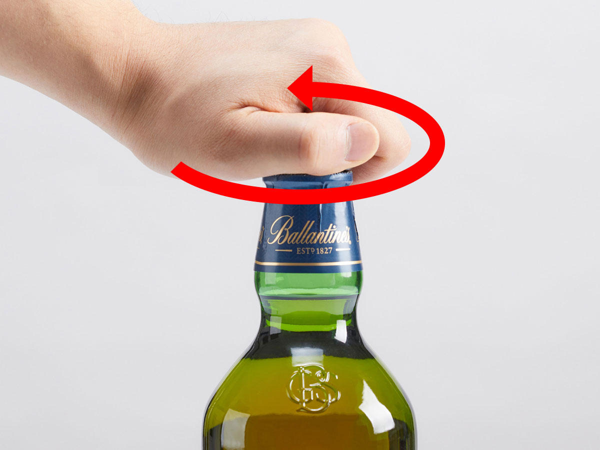 『バランタイン』＜21年＞＜17年＞＜17年トリビュートリリース＞の開け方解説の写真2。（2）片手で瓶の胴部分を押さえ、キャップを反時計回りに捻ります。