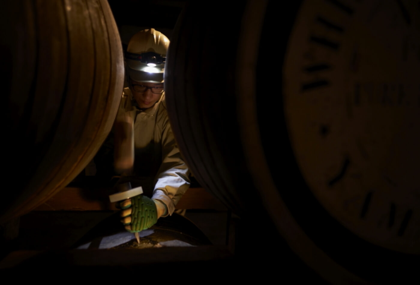貯蔵工程の職人がウイスキー樽を点検している画像